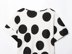 Detalle del cuello redondo y mangas cortas en una blusa blanca con lunares negros
