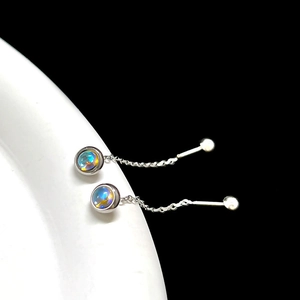Macro detail of silver moonstone tassel earrings with long chains on white curved stand