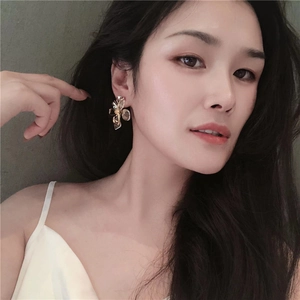 Elegant gold flower petal earrings with textured core worn by a fashion model