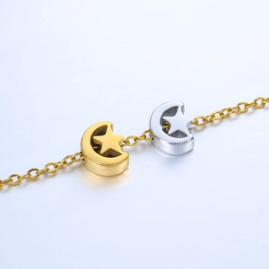 Close-up of polished gold and silver moon and star pendants on a delicate chain