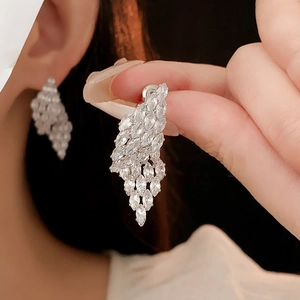 Detail of silver drop earrings with marquise zircon tassels held against the ear