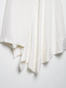 Detail shot of white linen blend fabric with minimalist asymmetric hem and weave texture