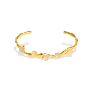 Irregular wavy gold stainless steel bangle with five translucent pastel beads on white background