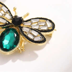 Macro shot of bee brooch featuring emerald-green gemstone and cubic zirconia accents