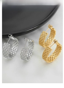 Detailed shot of woven texture hoop earrings in gold and silver finish on a marble surface