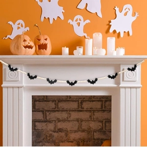 Halloween bat beaded garland hanging on a white fireplace with festive decor backdrop