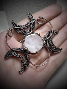 Detailed close-up of handmade bronze wire-wrapped quartz crystal pendant in hand