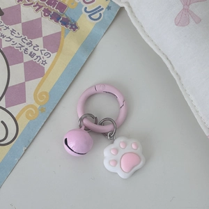 Close-up of pink cat paw bell pendant with a ring clasp and soft pastel heart details