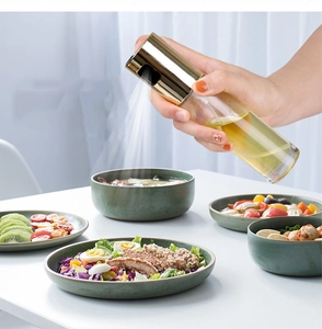 Close-up of golden oil sprayer bottle misting salad on a dining table scene