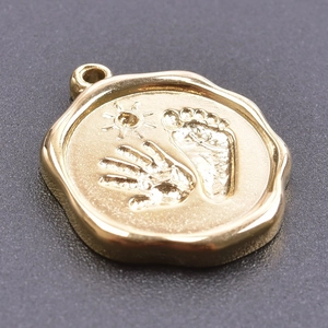 Macro view of gold stainless steel pendant featuring sun, handprint, and footprint relief