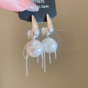Detail of silver bow pearl earrings with flowing bead chain tassels in a macro view