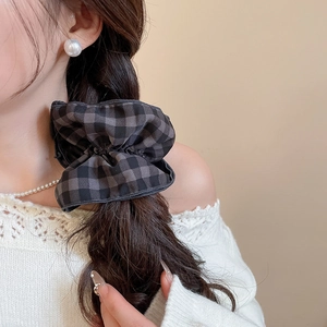 Detail eines Stoff-Haargummis mit Karomuster für elegantes Haarstyling im Pferdeschwanz