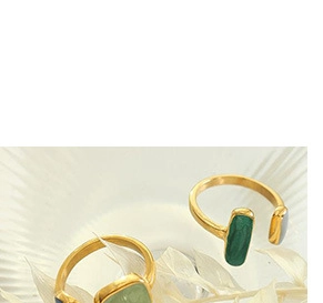 Close-up of retro gold rings with green malachite and translucent stones on a white tray