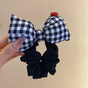 Detail of checkered bow hair scrunchie with red heart accent and pearl ribbon stripes