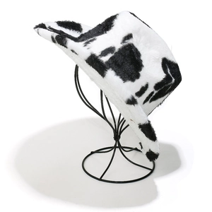 Vue latérale d'un chapeau de cowboy en peluche à motif vache sur un support noir