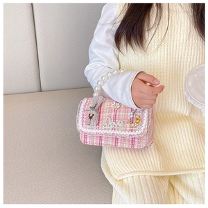 Detailed macro view of girls pink tweed crossbody bag with pearl handle and rabbit charm