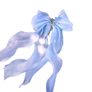 Blue princess bow hair clip with snowflake jewel, sheer ribbon, and white plush pom-poms