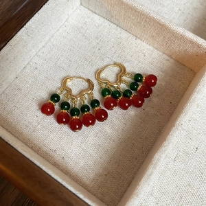 Macro shot of vintage gold earrings with red and green glass beads in a jewelry box