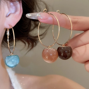 Detail showing resin round pendant earrings in light blue, pink and dark brown colors