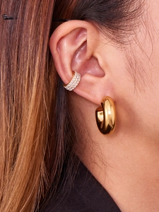 Detail shot of smooth hollow C-shaped earrings and sparkling zircon ear cuffs on ear