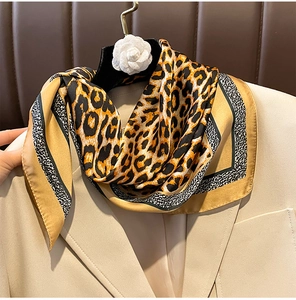 Close-up of leopard print silk scarf draped over a beige blazer showing fabric texture