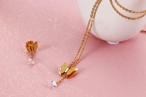 Detailansicht der goldenen Schmetterling-Halskette und Ohrringe mit Zirkonia auf Rosa