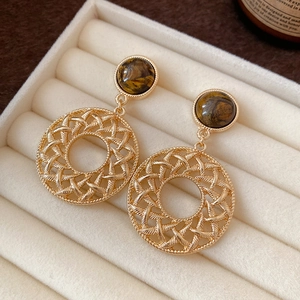Close-up of vintage gold earrings with tiger eye stone and intricate woven mesh pendant