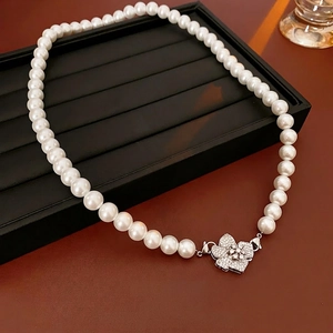 Elegant white pearl necklace featuring a floral zircon clasp on a black luxury display