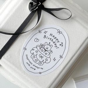 Close-up of Happy Birthday oval seal stickers with cute bear illustration on gift box
