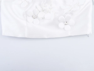 Detail of white fabric texture featuring 3D floral accents with sparkling rhinestones