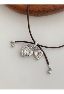 Macro detail of silver heart pendant with radiant texture and zircon on brown cord