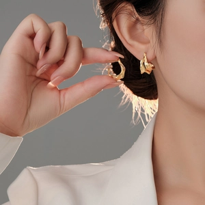 Detailed view of irregular gold foil texture earrings with a brushed metal finish on model