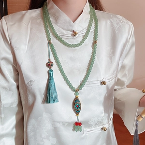 Close-up of light green crystal beaded necklace with vintage tassel and enamel pendant