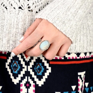 Close-up of vintage oval moonstone ring with silver band worn on a model finger