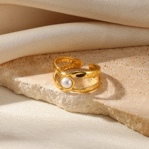 Close-up of golden pearl double-layer ring with textured finish on beige stone