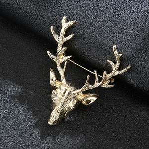 Macro view of a gold-tone reindeer head brooch on a textured black leather background