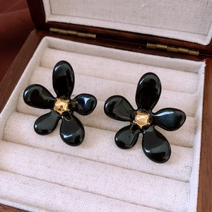 Vue macro de boucles d'oreilles fleurs noires à cinq pétales avec centre doré