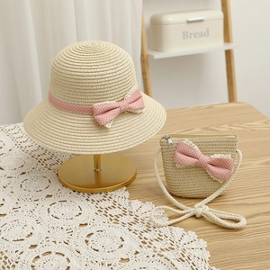 Detail of straw hat and crossbody bag set with pink polka dot bows on lace fabric