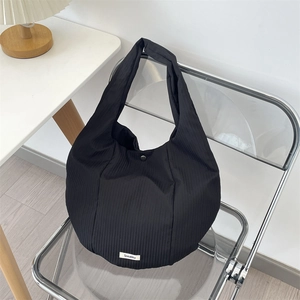 Détail du sac cabas plissé noir avec étiquette Sozakka sur chaise moderne