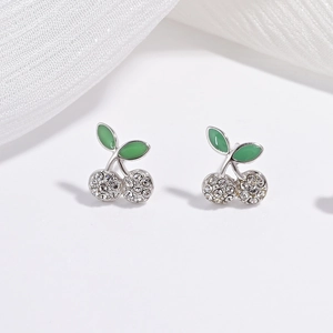 Macro shot of silver cherry earrings with green enamel leaves and sparkling crystal pavé