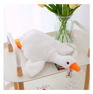 Close-up of white plush goose bag with orange beak on a cream cart with yellow tulips