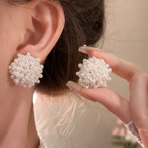 Elegant white pearl cluster ball earrings on a silver pin shown on a model