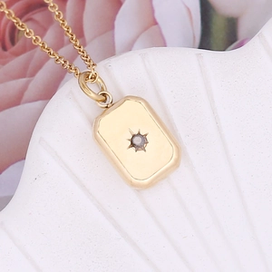 Irregular geometric pendant necklace in gold with starburst pattern and small gemstone