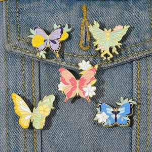 Set of five colorful floral butterfly enamel pins on a classic blue denim jacket pocket