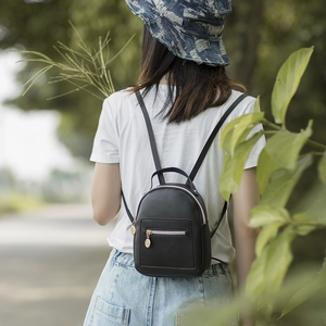 Fashionable black PU leather mini backpack for women with gold zippers in outdoor setting