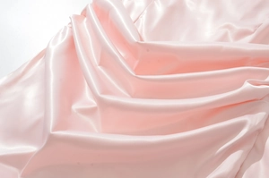 Gros plan sur le satin rose avec texture soyeuse et drapé élégant pour robe moulante