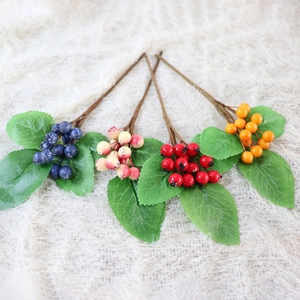 Detailed view of artificial berry stems in four colors with lifelike green leaves