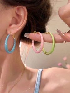 Detail of colorful enamel hoop earrings in candy blue, pink, and green with gold hooks
