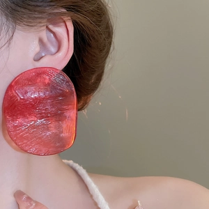 Close-up of model wearing large red irregular resin hoop earrings with texture