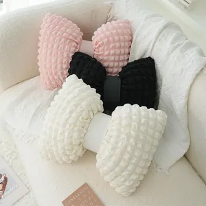 Bow-shaped puff lattice sofa cushions in pink, black, and white on a cream sofa